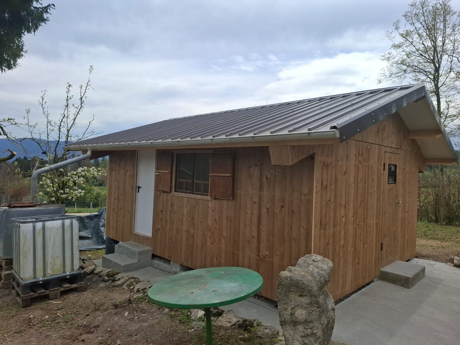 Small timber outbuilding with natural wood cladding in a Swiss garden setting