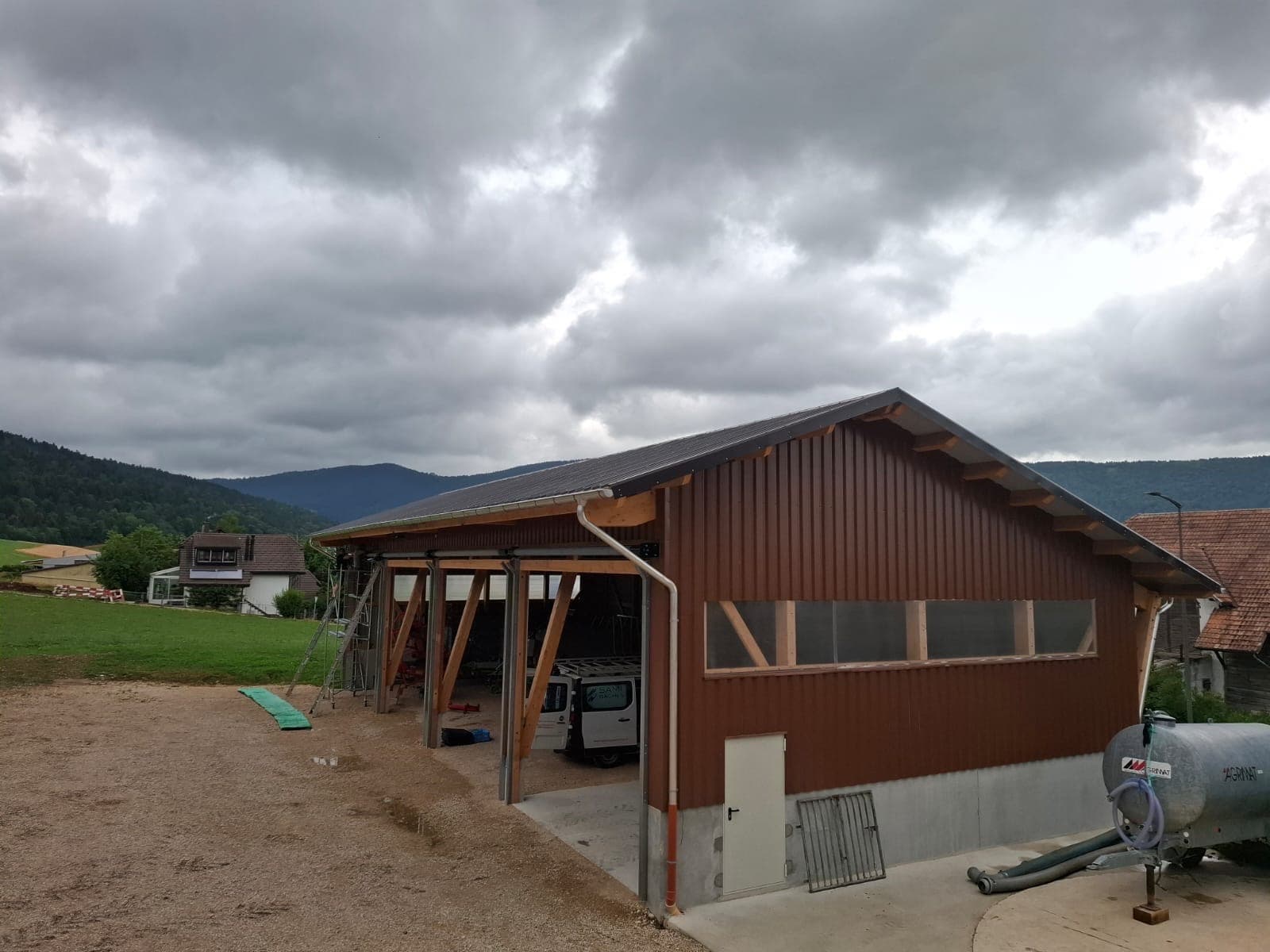 Agricultural hall under construction with open timber bays and mountain backdrop
