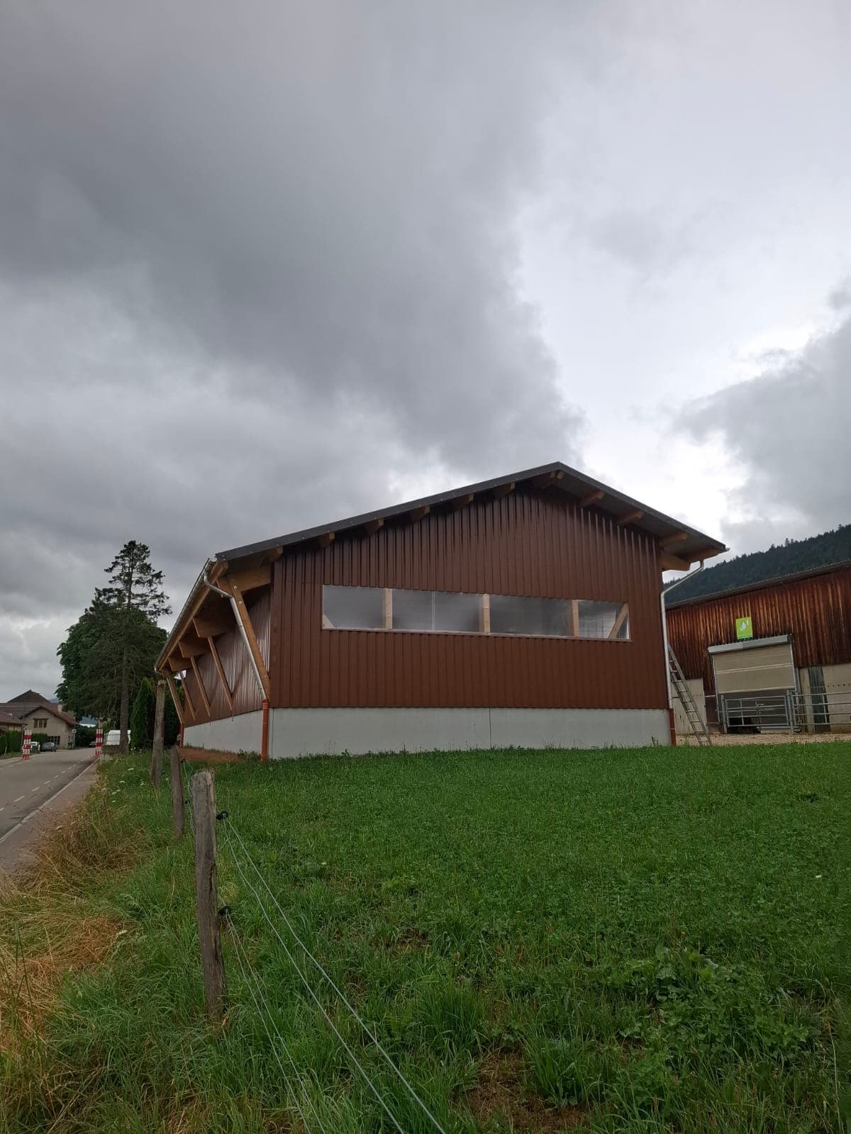 Agricultural hall with corrugated metal cladding beside green pasture