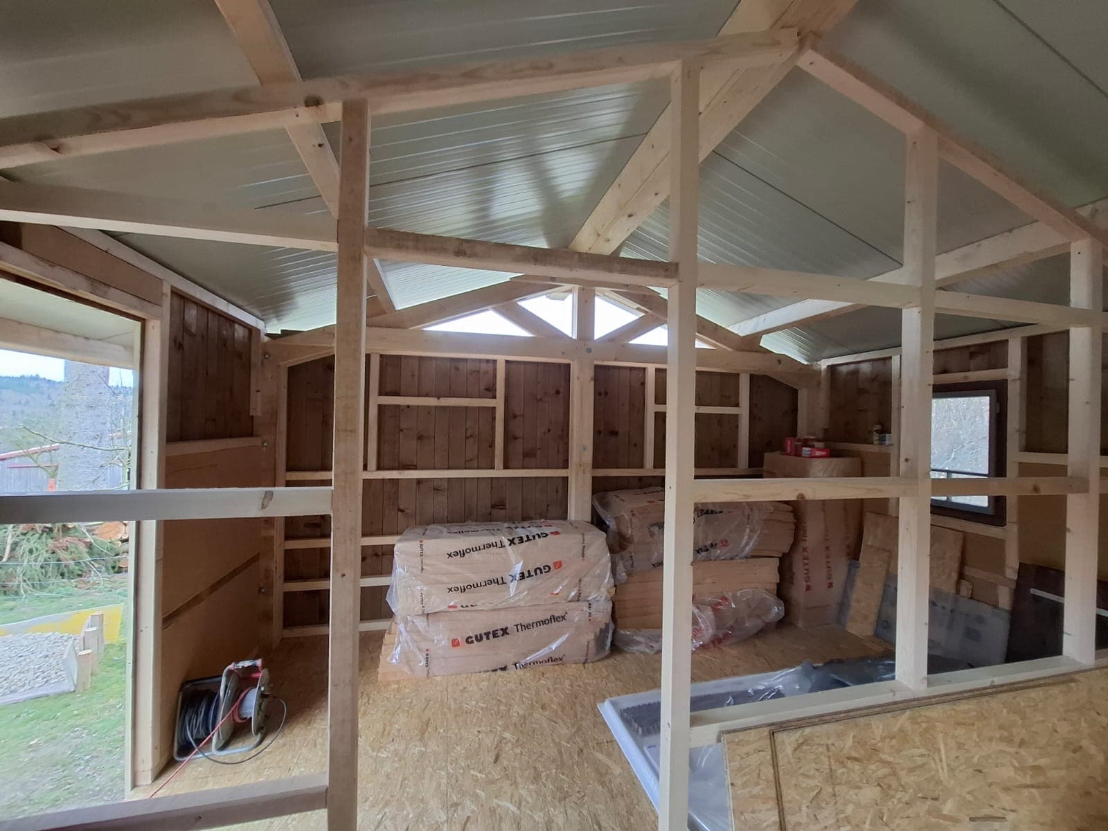 Interior timber frame structure showing exposed roof trusses and wooden walls